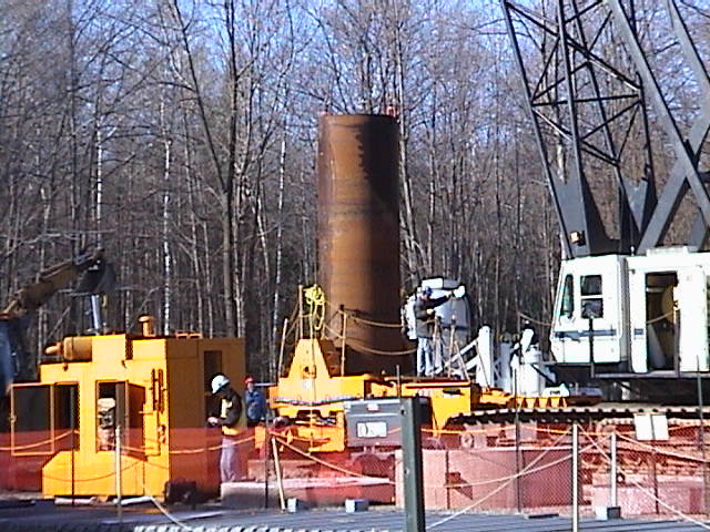 An outer core barrel is being loaded into the oscillator in preparation of oscillating into the ground around the perimeter of a Tile Hole.